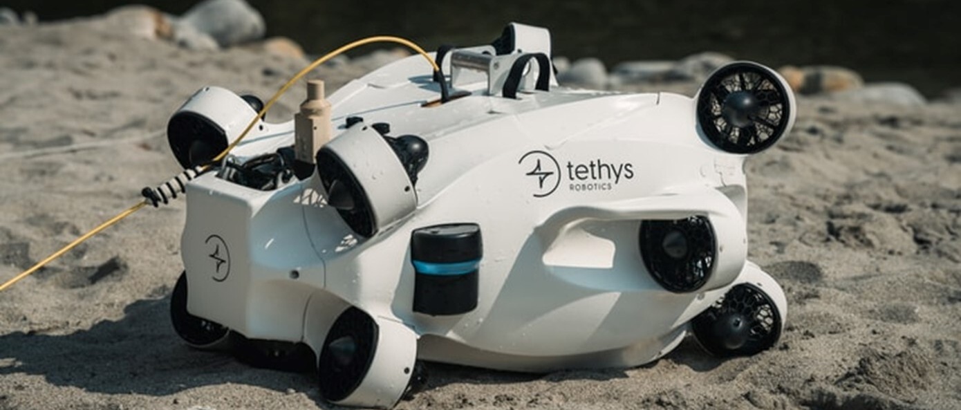 Der weisse Tauchroboter Tethys ONE liegt auf hellem Sand